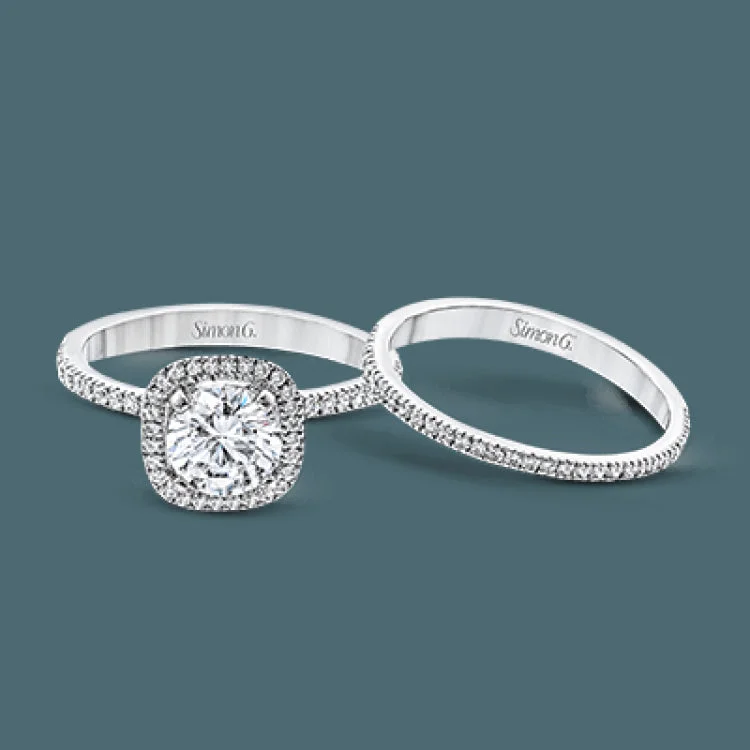 Women’s modern engagement rings-Accented by .46 ctw of glistening round cut white diamonds, this contemporary white gold halo style engagement ring and wedding band set makes a dramatic statement.